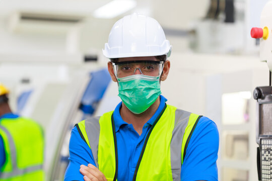 Close Up Head Shot Young Asian Man Applying Protective Face Mask   Wearing Glasses Looking At Camera. Factory Worker At The Workplace