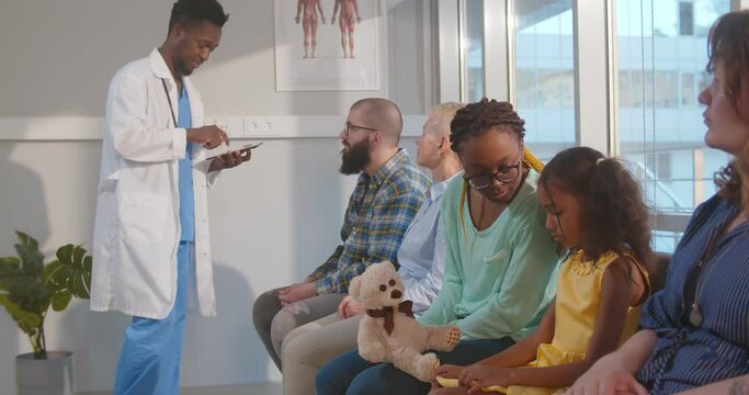 Multiethnic patients waiting in queue in clinic hall.