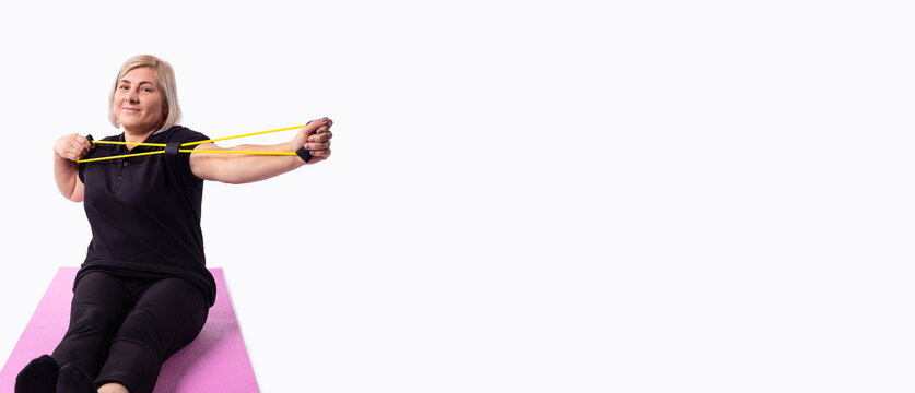 Banner, long format, grey background with space for your ad. Caucasian female sportswoman, fitness trainer doing stretching exercises for muscles using an elastic band wearing sportswear