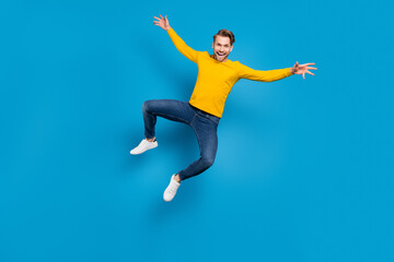 Fototapeta na wymiar Full length body size of young guy jumping up cheerful laughing careless playful isolated bright blue color background