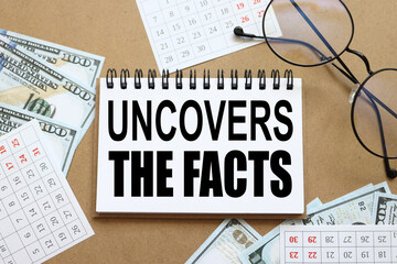 Uncover the facts concept. text on white notepad paper near calendar on wood craft background