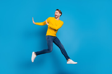 Fototapeta na wymiar Full length body size of young guy jumping running away rejecting refusing isolated vibrant blue color background