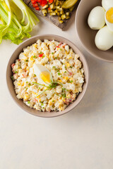 A light egg salad with celery, gherkin, pepper and mayonnaise. Served in a bowl on a light background. Top view.