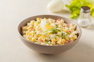 A light egg salad with celery, gherkin, pepper and mayonnaise. Served in a bowl on a light background. Front view.