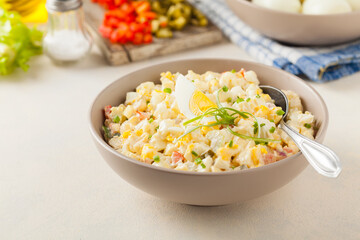A light egg salad with celery, gherkin, pepper and mayonnaise. Served in a bowl on a light background. Front view.