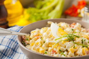 A light egg salad with celery, gherkin, pepper and mayonnaise. Served in a bowl on a light background. Front view.