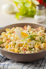 A light egg salad with celery, gherkin, pepper and mayonnaise. Served in a bowl on a light background. Front view.