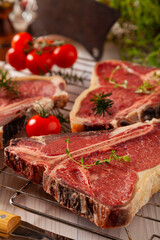Raw t bone steak, with herbs. Grill accessories. Ready for grilling. Wooden bright background.