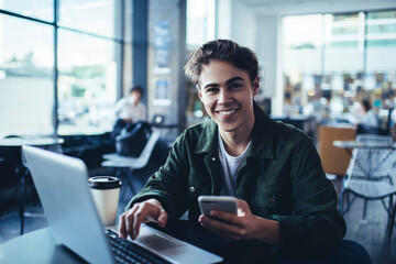 Delighted man with laptop surfing smartphone