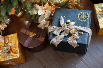 Christmas boxes with gifts under a Christmas tree on a dark floor. Multicolored boxes with ribbons and decorations.