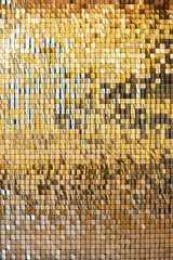Gold glittering squares on the wall, interior decor, background. Vertical photo