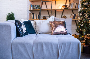 Several shiny and beige decorative pillows on a cozy sofa, interior.