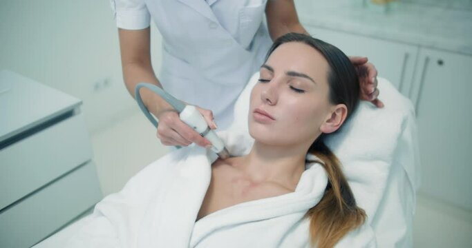A close-up female client in a bathrobe is having a non-injection bio-revitalization procedure by using the Dermadrop TDA device.