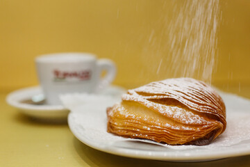 Sfogliatella riccia napoletana mentre viene guarnita con dello zucchero a velo