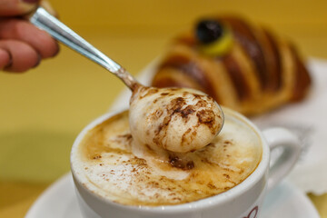 Cappuccino cremoso mentre viene girato con un cucchiaino