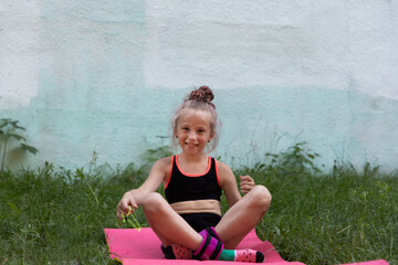 Portrait of girl gymnast sitting on mat and smiling on training outdoors