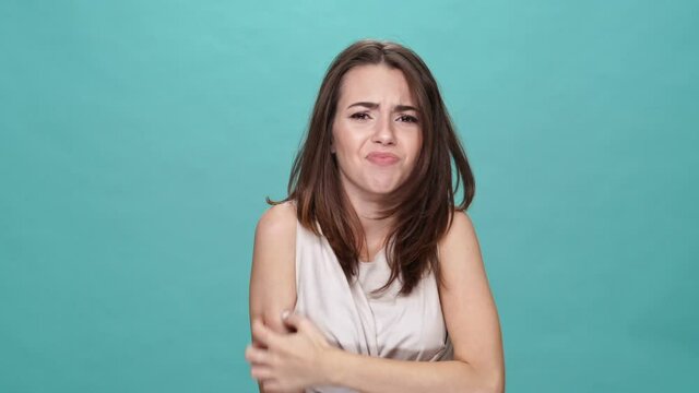 Beauty brunette woman in t-shirt itches all over turquoise background