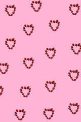 Pattern of strawberries in the shape of hearts on a pink background
