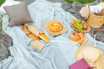Accessories, hats and basket, picnic on the lawn on a blanket with baguette, croissants, grapes