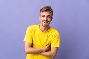 Young handsome blonde man isolated on purple background smiling a lot