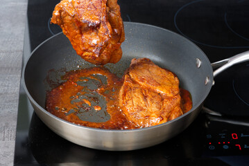 Pork steak with sauce fried in a frying pan at home