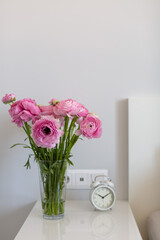 flowers ranunculus azur deep pink on the bedside table in the bedroom