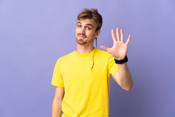 Young handsome blonde man isolated on purple background counting five with fingers