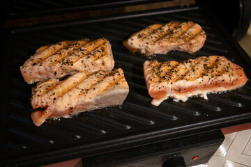 The process of frying salmon fillets at home on an electric grill