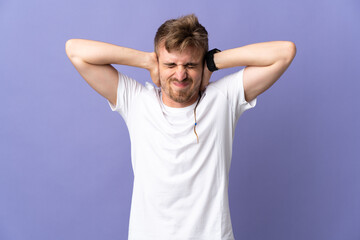 Fototapeta na wymiar Young handsome blonde man isolated on purple background frustrated and covering ears