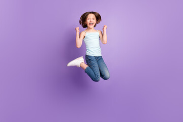 Full body photo of cute brown hairdo small girl jump hands fists wear blue top jeans isolated on...