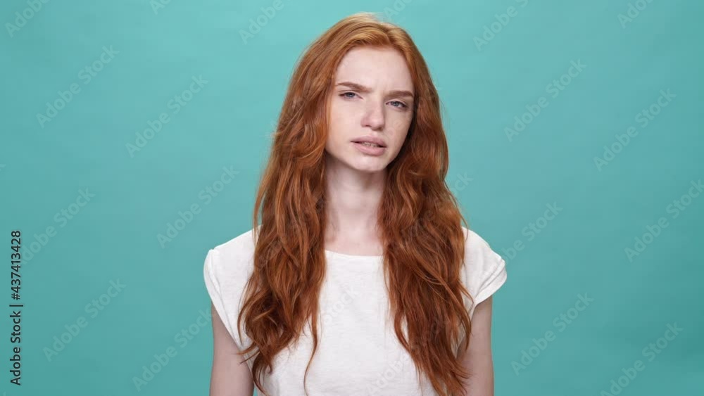 Wall mural Bored ginger woman in t-shirt yawns and looking at the camera over turquoise background