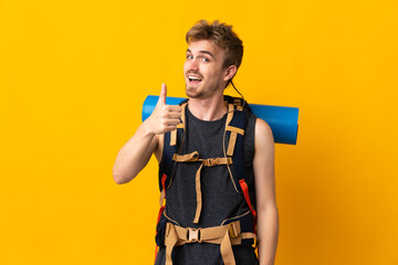 Young mountaineer man with a big backpack isolated on yellow background with thumbs up because something good has happened
