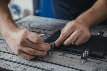 The worker fixes the rubber blank of the product on the machine with a key. Work in production. Production of automobile spare parts. Close-up.