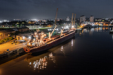 Fototapeta na wymiar A Ship Docked at Port at Night Awaiting Cargo for Shipping