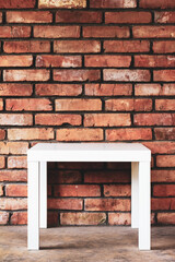 an empty white table against a brick wall