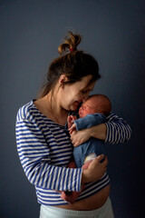 small baby with mom, baby, on a blue isolated background, sweet crying of a newborn baby in mom's arms, selective focus