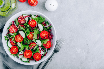 Green salad bowl with tomatoes, cucumbers, red onions, radicchio and fresh lettuce.