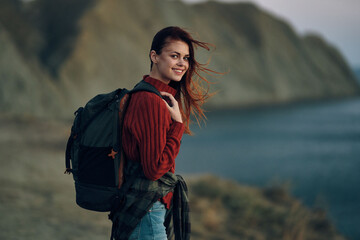 traveler with a backpack in a sweater and jeans near the sea in the mountains Copy Space