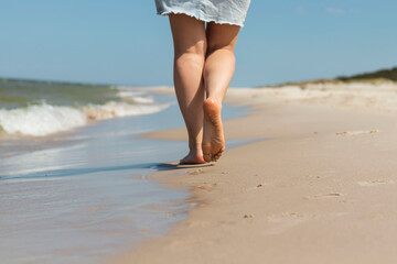 Beautiful legs of a young girl walk along the beach