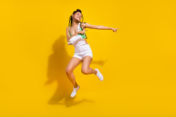 Fototapeta na wymiar Full body photo of afro american funky happy young woman jump up dance isolated on yellow color background