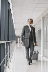 Senior businessman with travel suitcase in airport