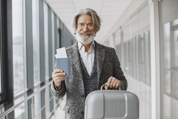 Senior businessman with travel suitcase in airport