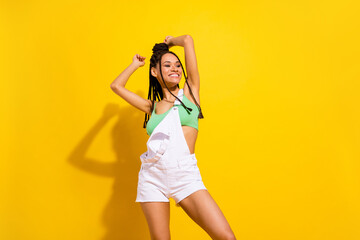 Photo of attractive young dark skin happy woman dance raise hands smile isolated on yellow color background