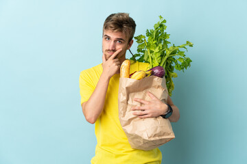 blonde Person taking a bag of takeaway food isolated on blue background thinking