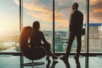 Silhouettes of two entrepreneurs on the top floor of a business high-rise, enjoying the sunset...