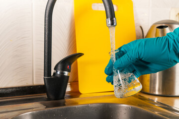 water purification specialist tap water pours into a glass flask.