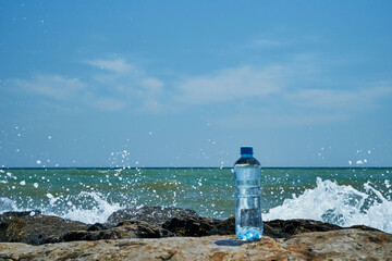 Plastic bottle. Coast of the sea. Waves hit the stones.