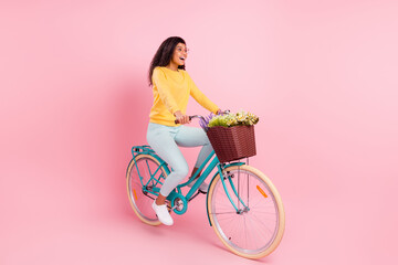 Portrait of attractive amazed cheerful girl riding bike having fun isolated over pastel pink color background