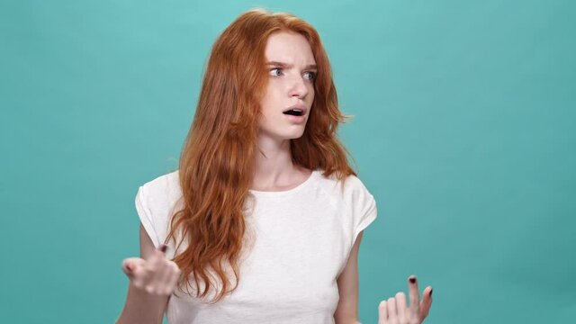 Confused ginger woman in panic over turquoise background