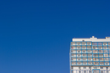 Bottom view of the facade of a high residential building against a blue sky